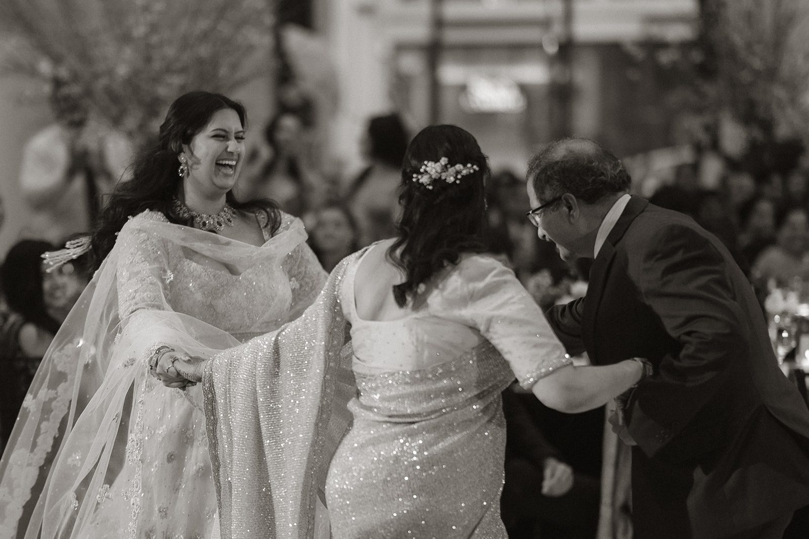 Black-and-white candid of family members laughing and dancing together during a multi-day wedding reception in San Francisco.