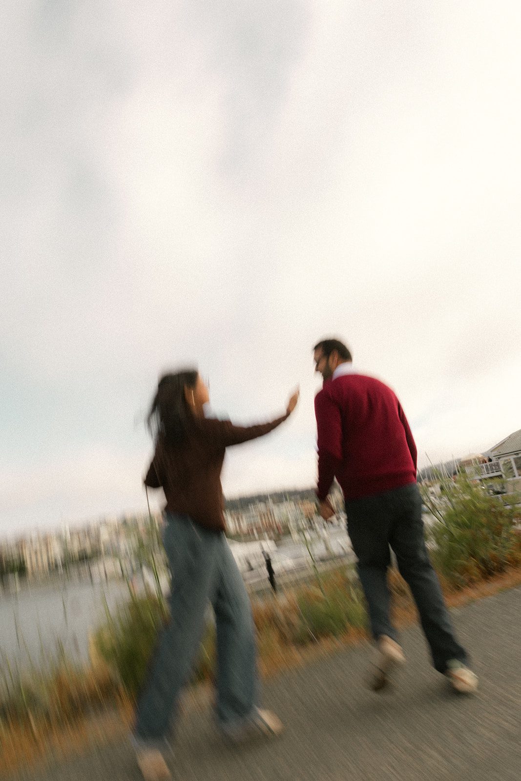 Motion-blurred couple walking hand in hand beside a marina, adding movement and spontaneity to engagement photography in San Francisco.