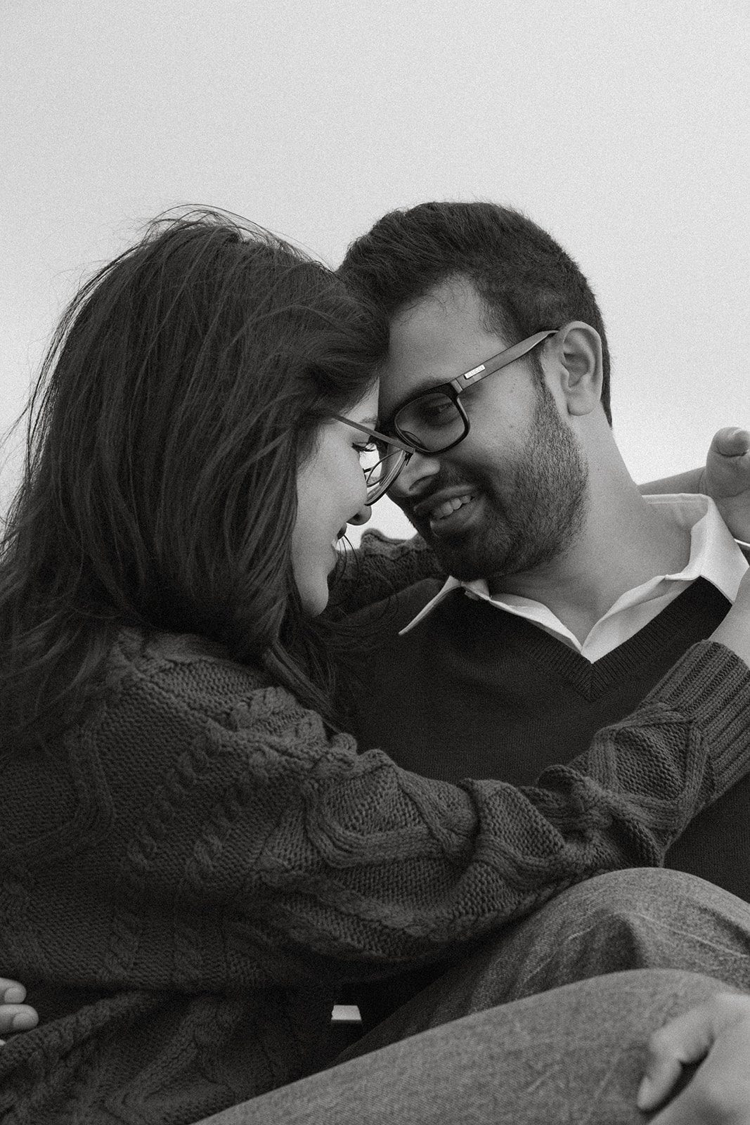Black-and-white close-up of a couple leaning forehead to forehead in a quiet candid moment, an intimate example of engagement photo ideas.