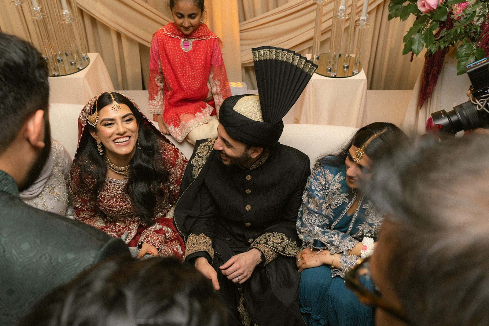 Bride and groom in traditional attire surrounded by family during their south asian wedding ceremony.