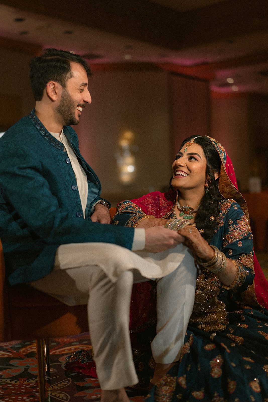 Couple in coordinated teal traditional attire sharing a candid moment during their multi day wedding celebration.