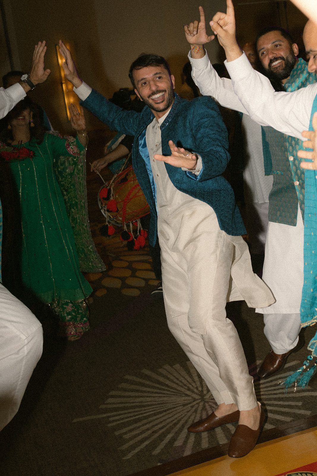 Groom dancing with guests in colorful traditional clothing during a lively multi day wedding celebration.