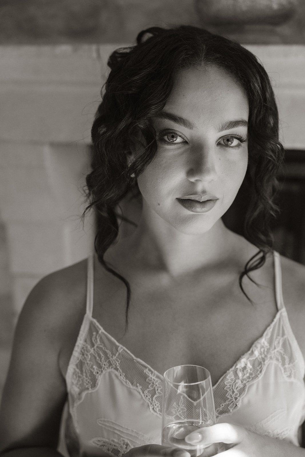 Intimate black and white bridal portrait featuring soft curls, delicate lace detailing, and a champagne glass at the European inspired wedding venue Sunstone Villa.