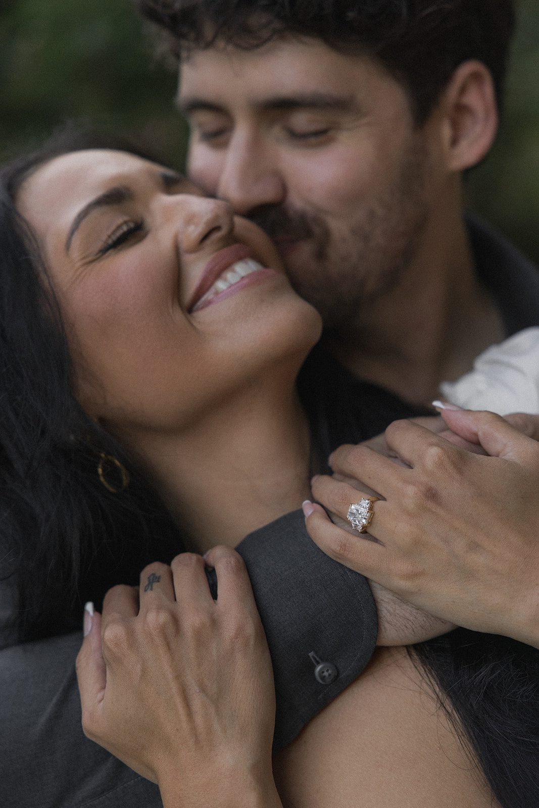 Close-up portrait of an engaged couple embracing with her engagement ring prominently visible, captured by a Bay Area wedding photographer.