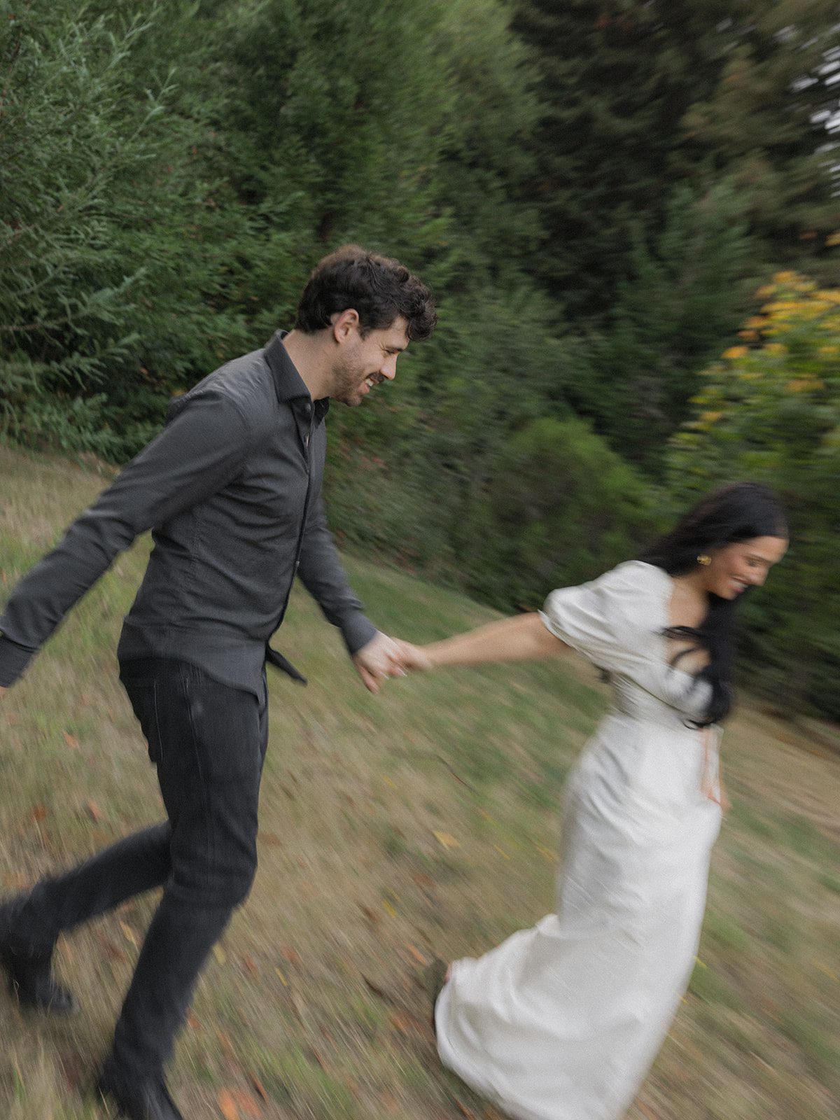 Engaged couple running hand in hand through a forest clearing during Reinhardt Redwood Regional Park Engagement Photos.