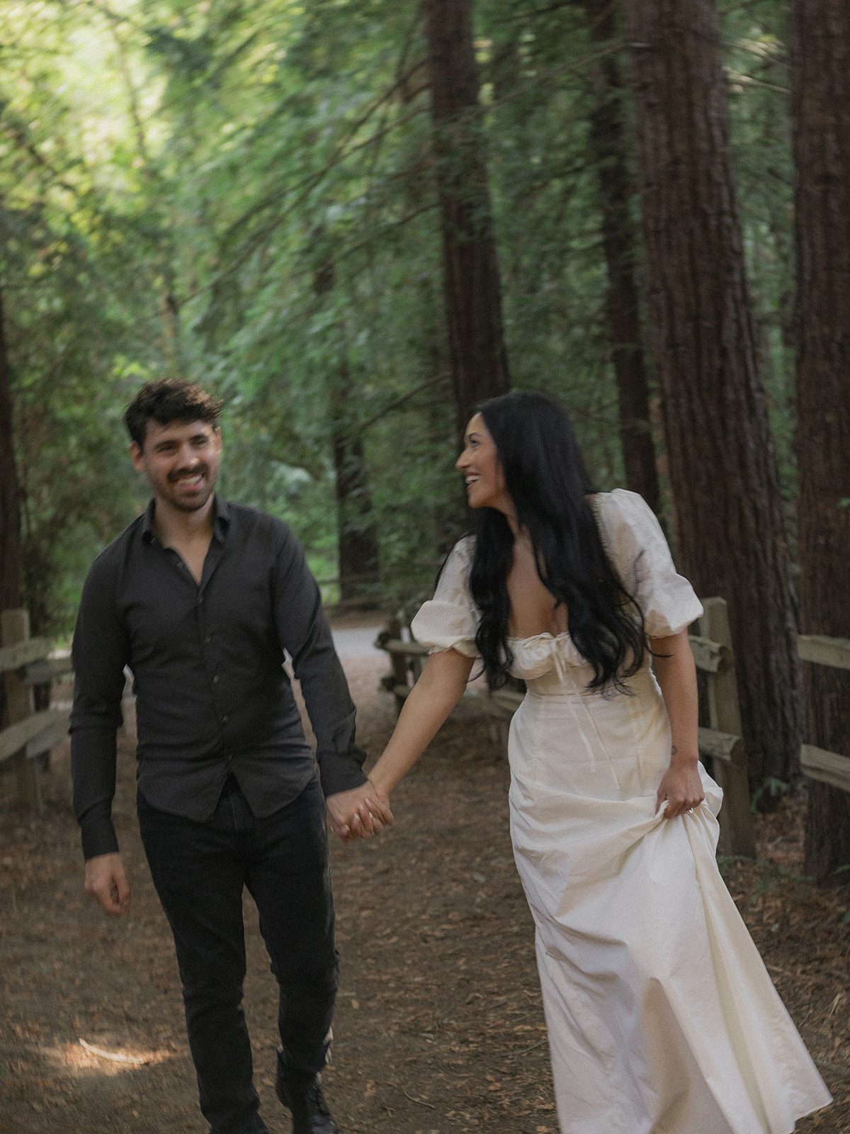 Couple walking hand in hand along a shaded redwood trail, captured by a Bay Area wedding photographer for natural forest engagement photos.