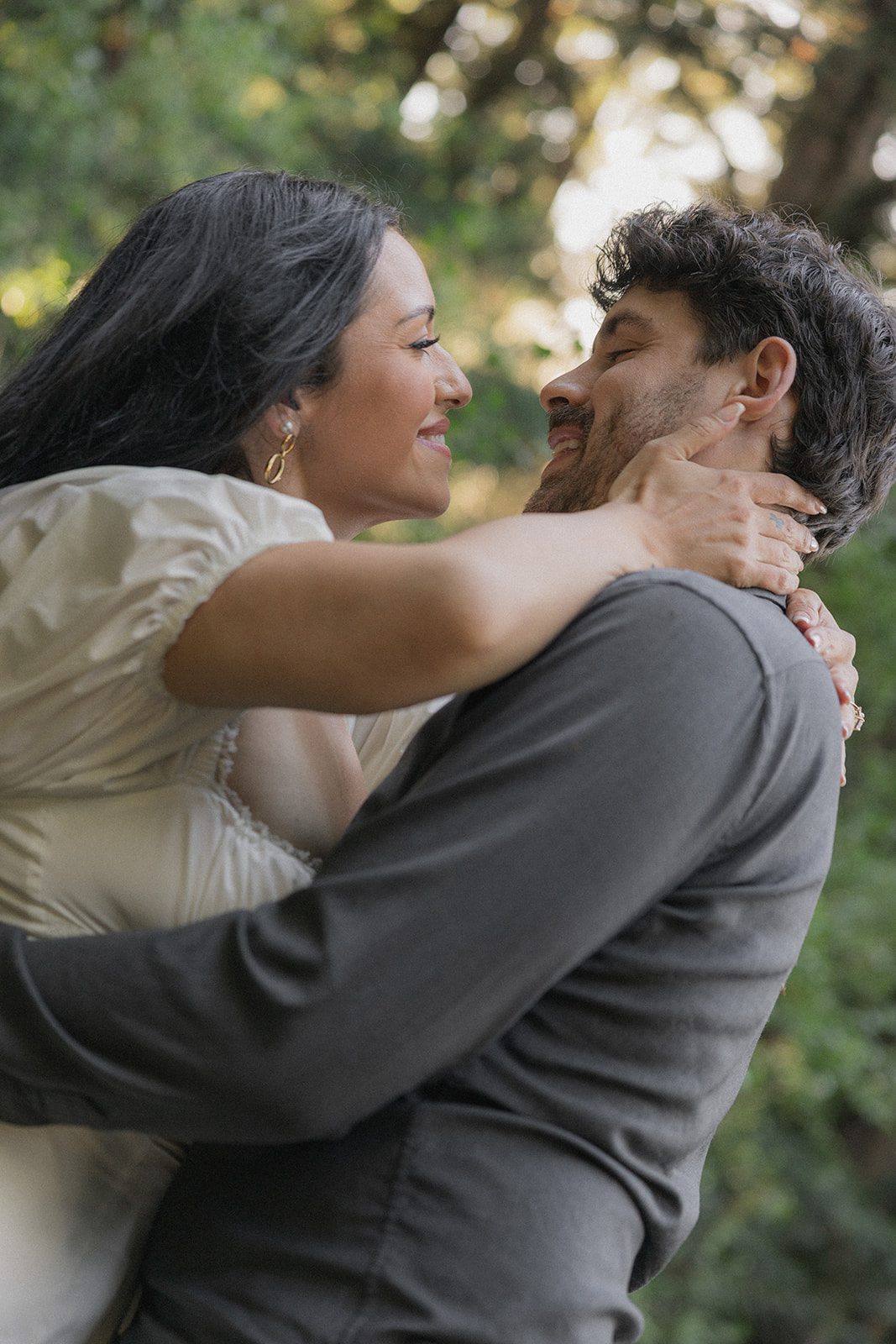 Engaged couple embracing closely outdoors with soft greenery behind them during Northern California engagement photos.