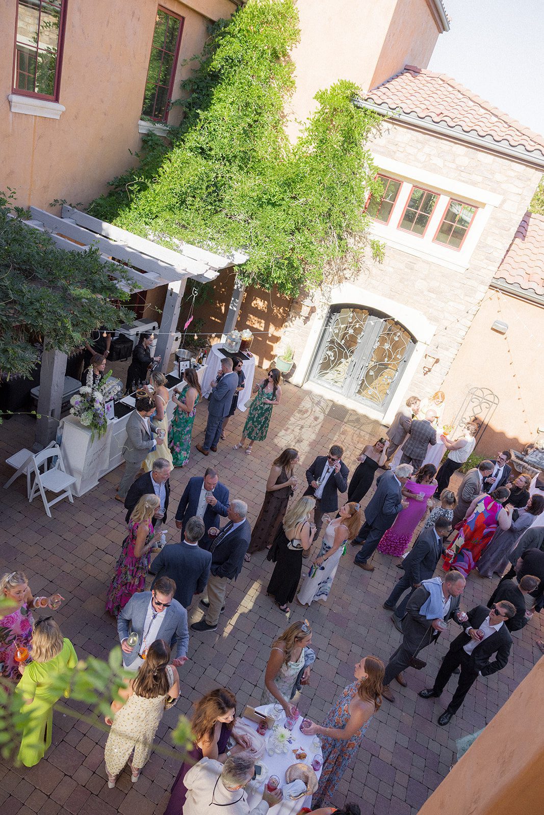 Overhead view of wedding guests mingling beneath string lights in the Tuscan-inspired courtyard at Villa San Juliette wedding venue.