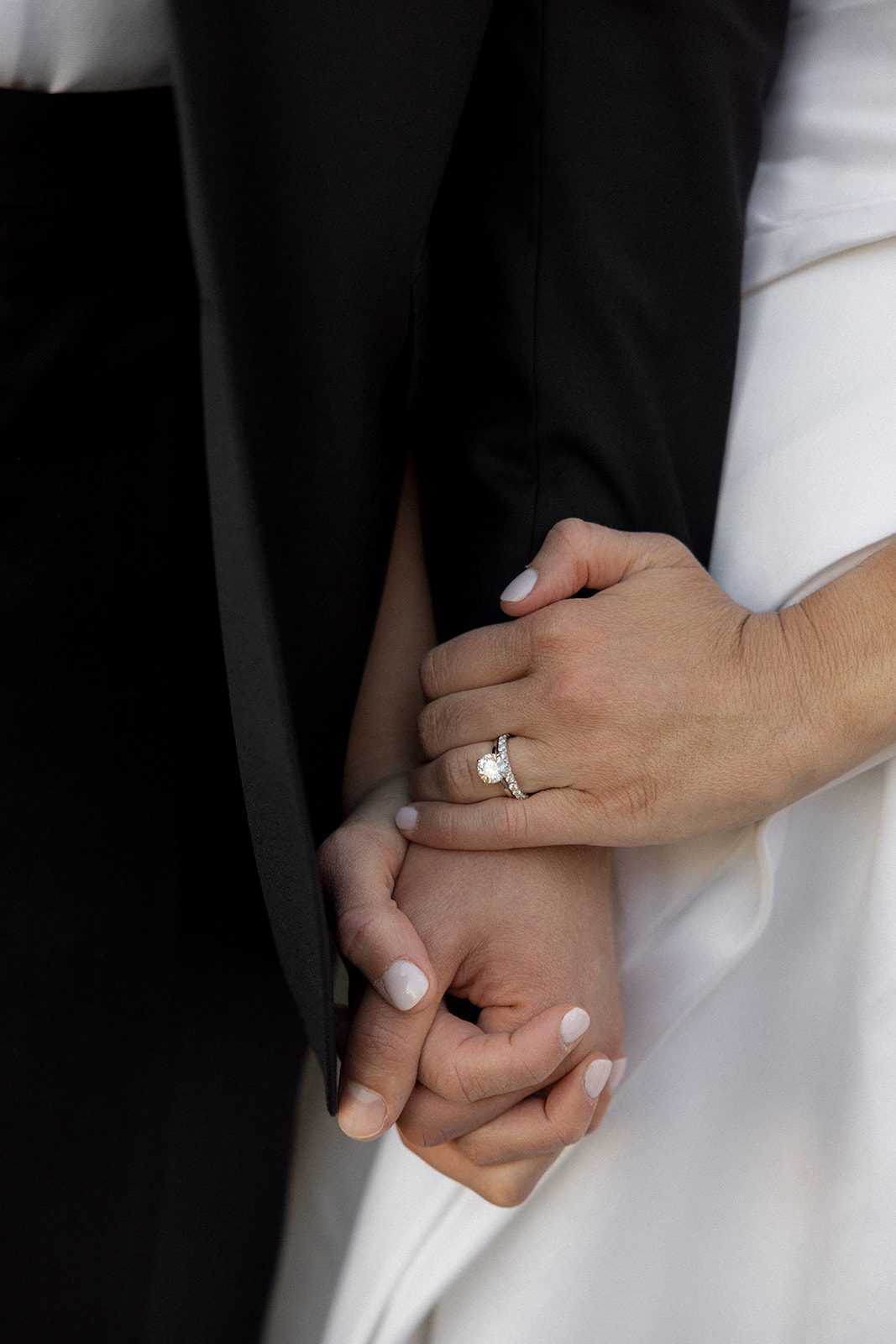 Close-up of a bride's diamond engagement ring and wedding band as she holds her groom's hand during their san luis obispo wedding.