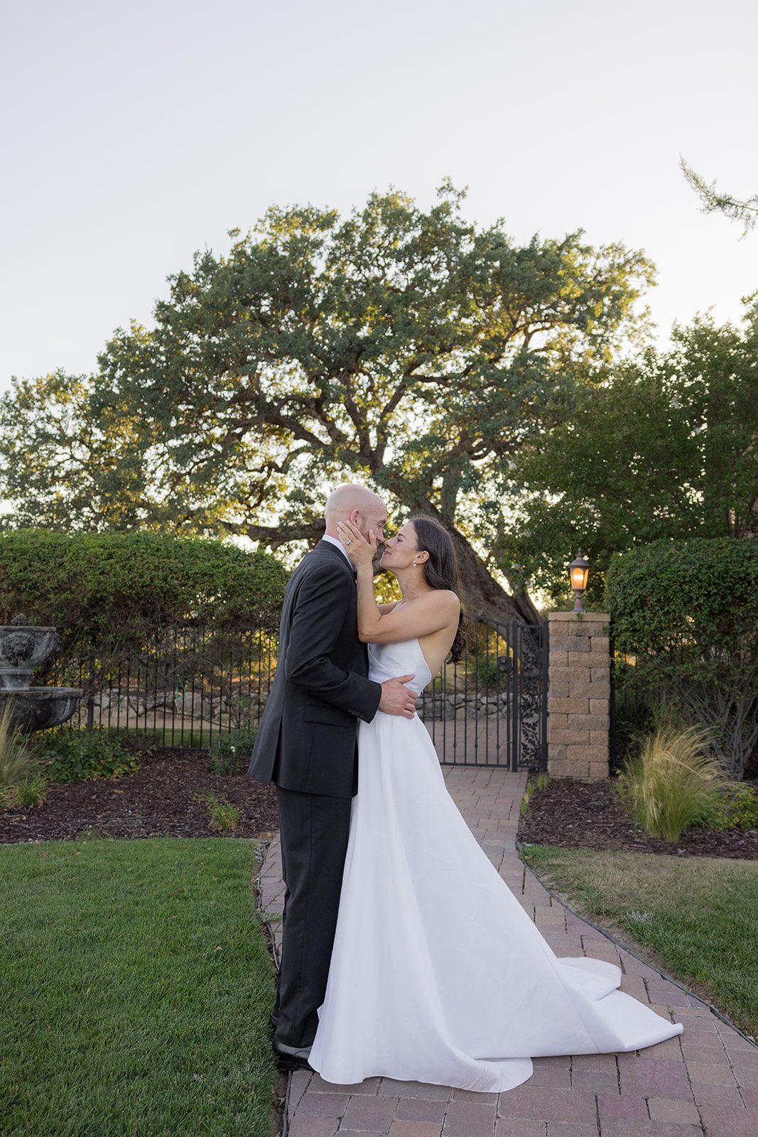 Bride and groom kissing beneath a sprawling oak tree during their Villa San Juliette wedding portraits in California wine country.