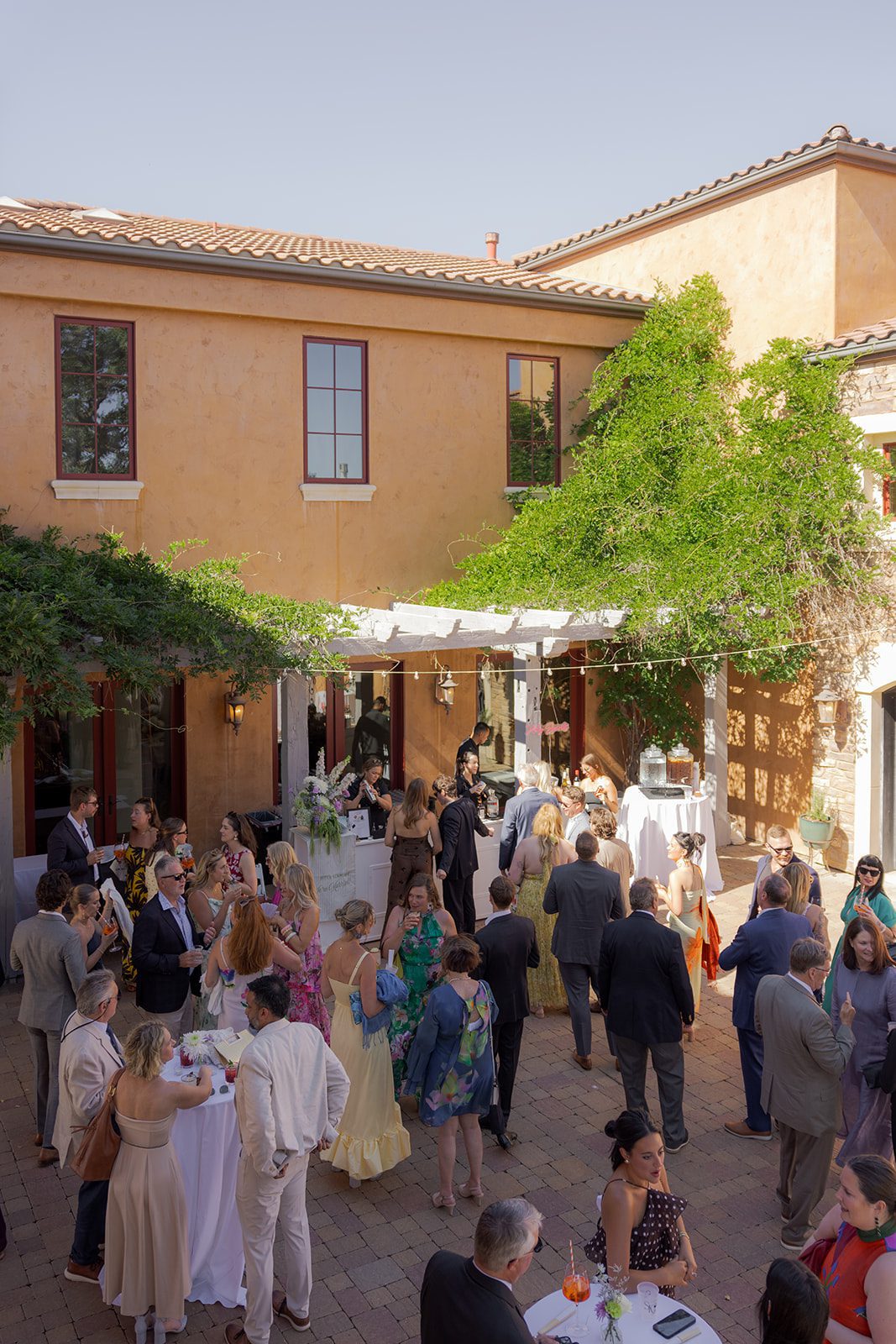Wedding guests mingling during an outdoor courtyard cocktail hour at a Tuscan-inspired vineyard wedding venue near San Luis Obispo.
